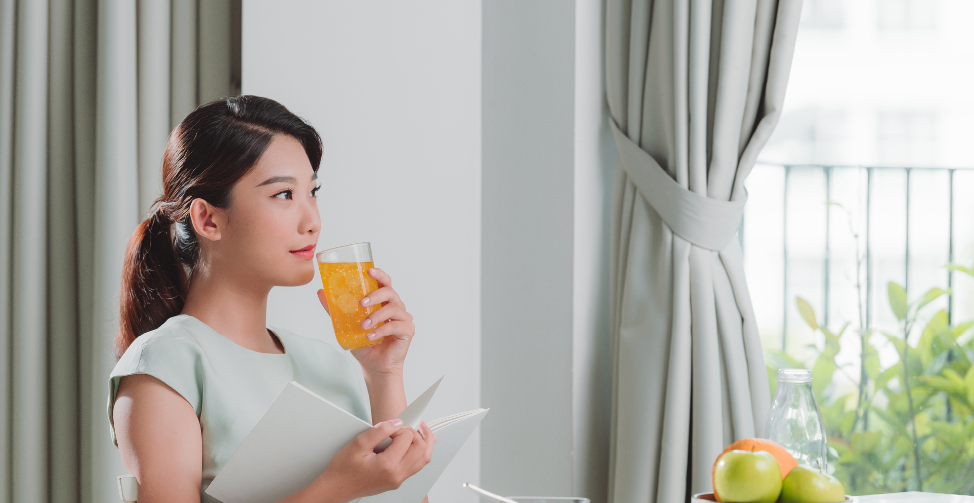 A woman enjoying an iced orange drink at home